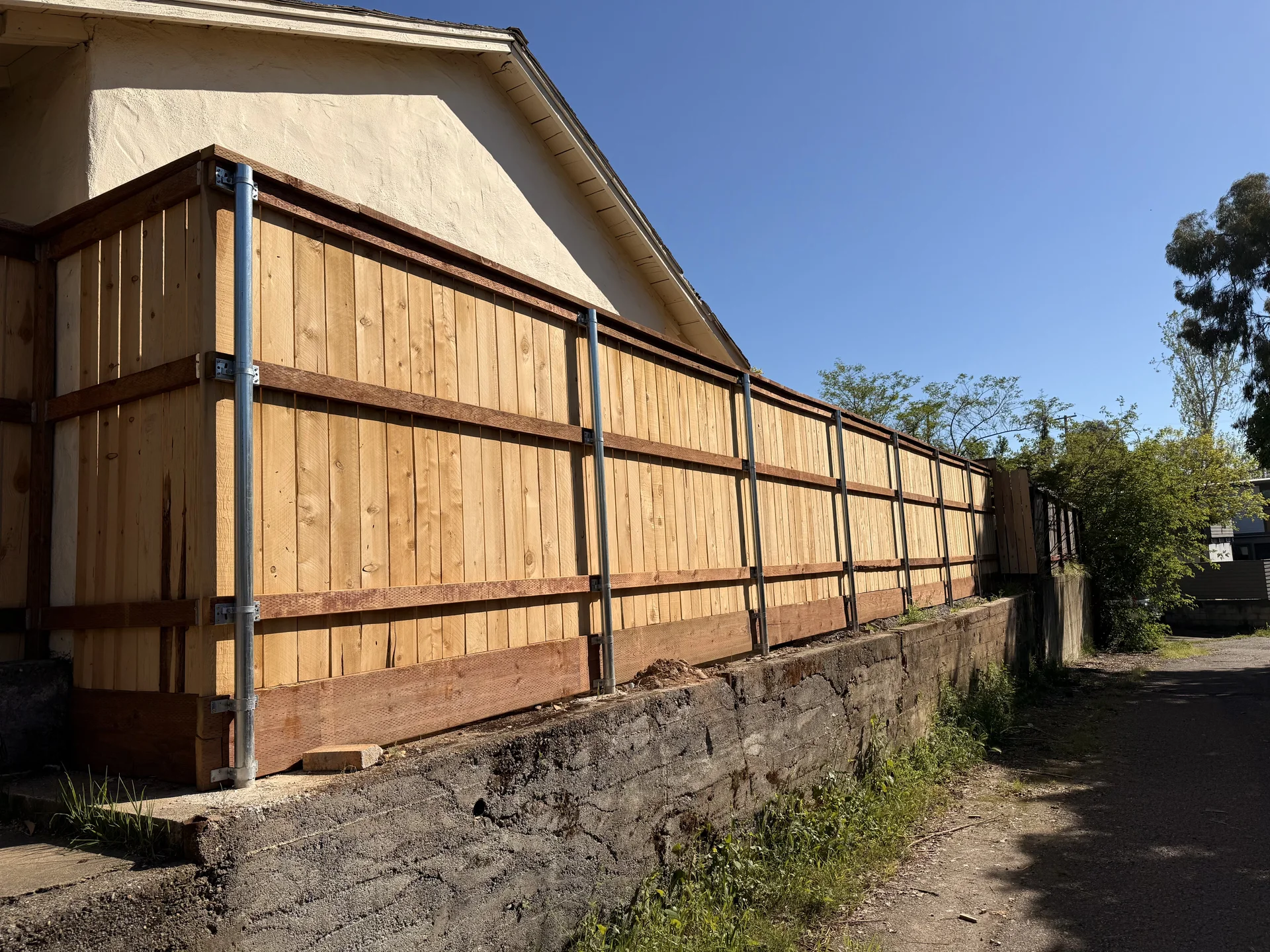 Long cedar privacy fence with steel posts on retaining wall