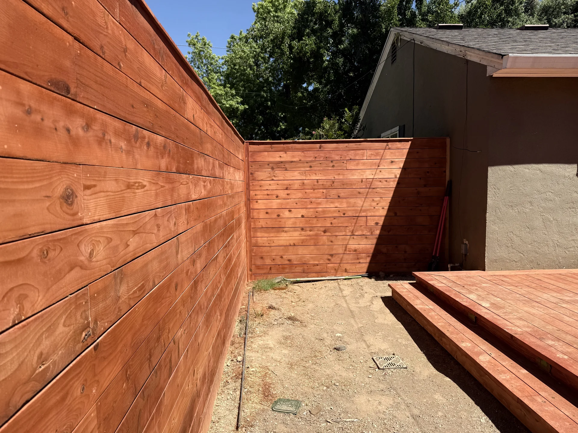 Horizontal redwood fence with matching deck in backyard